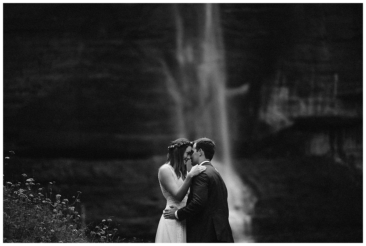 Bride and groom embrace in front of waterfall at Bridal Veil Falls in Telluride, Colorado. 
