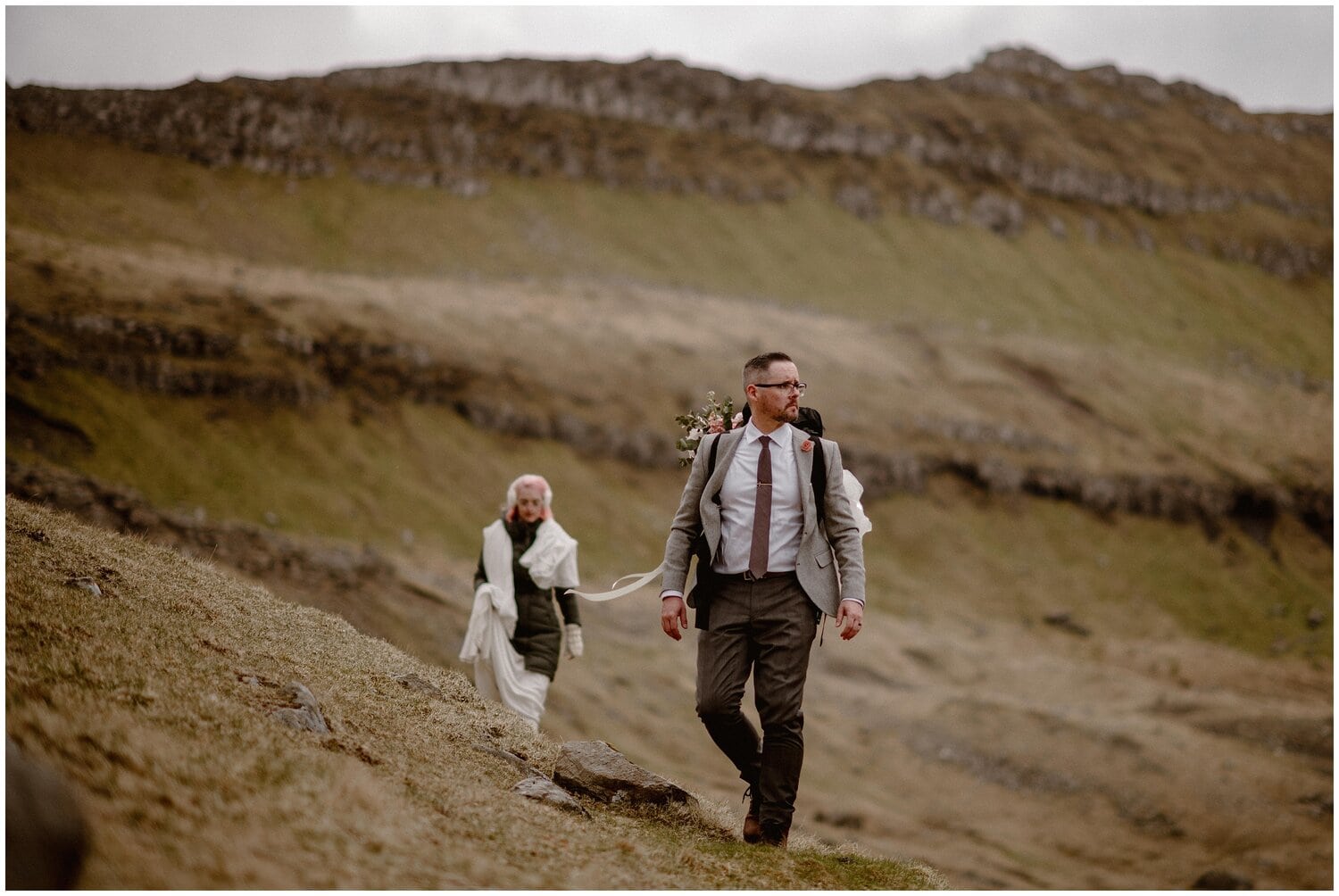 Bride and groom hike on trail at Faroe Islands. 