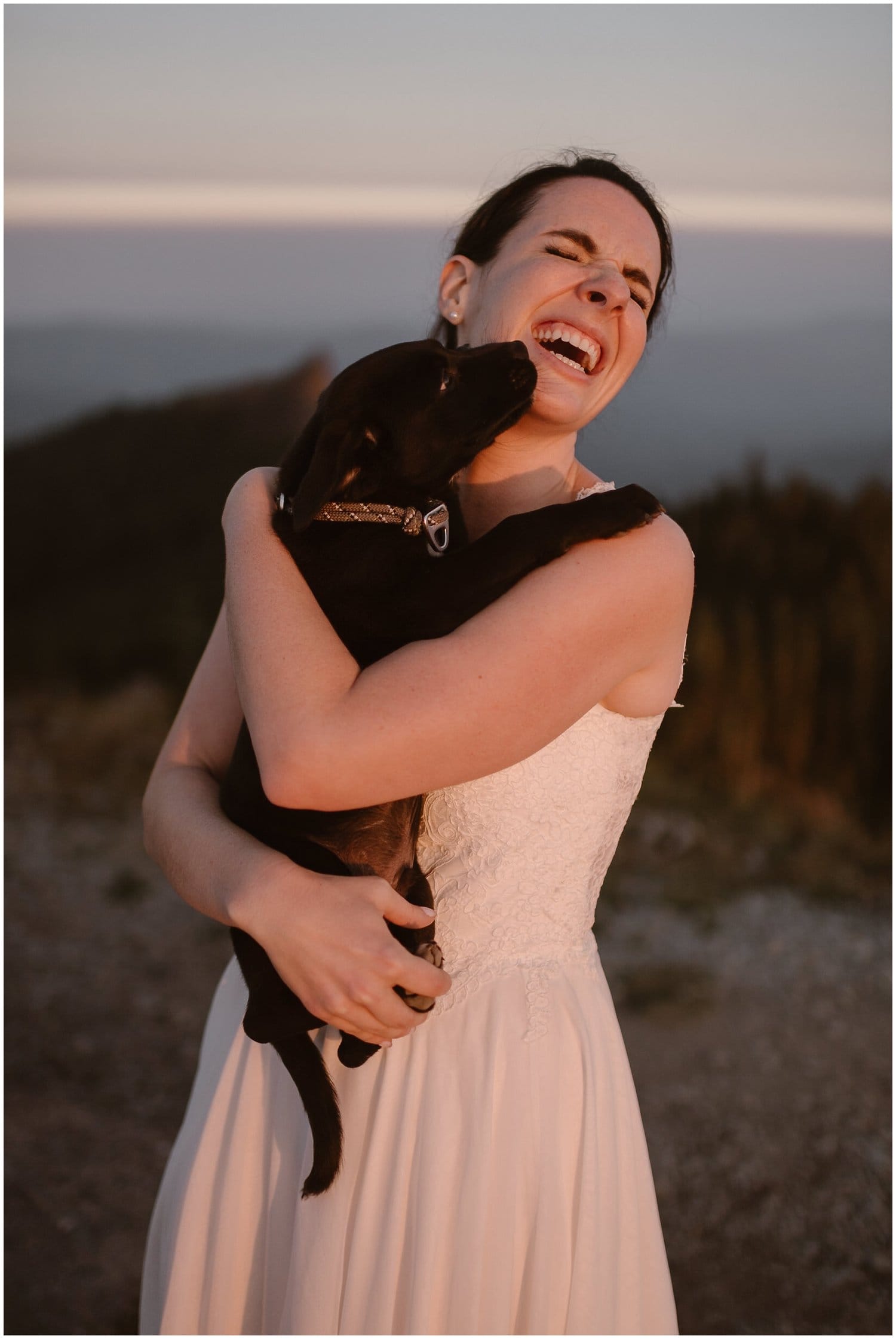 Bride holding a puppy and laughing.
