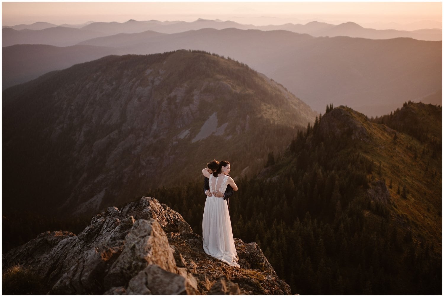 Bride and groom embrace on top of a cliff, during a sunrise hike in Washington. 