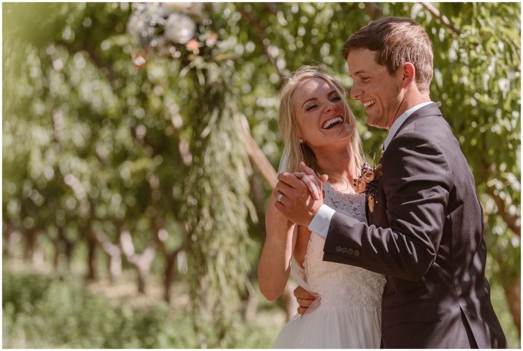 Bride and groom dance in peach orchard in Palisade, Colorado. 