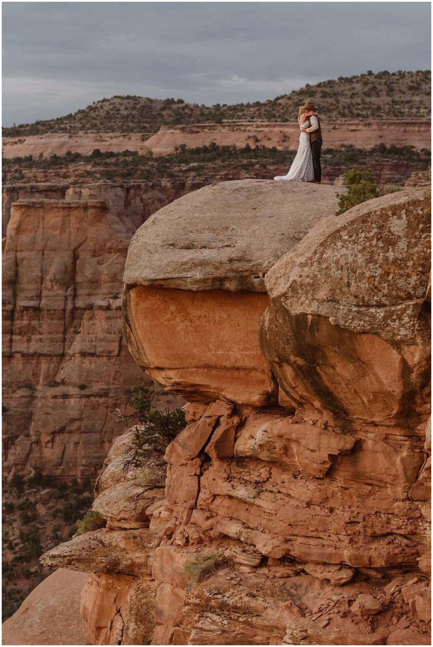 Bride and groom embrace on top of cliff overlook at Colorado National Monument. 