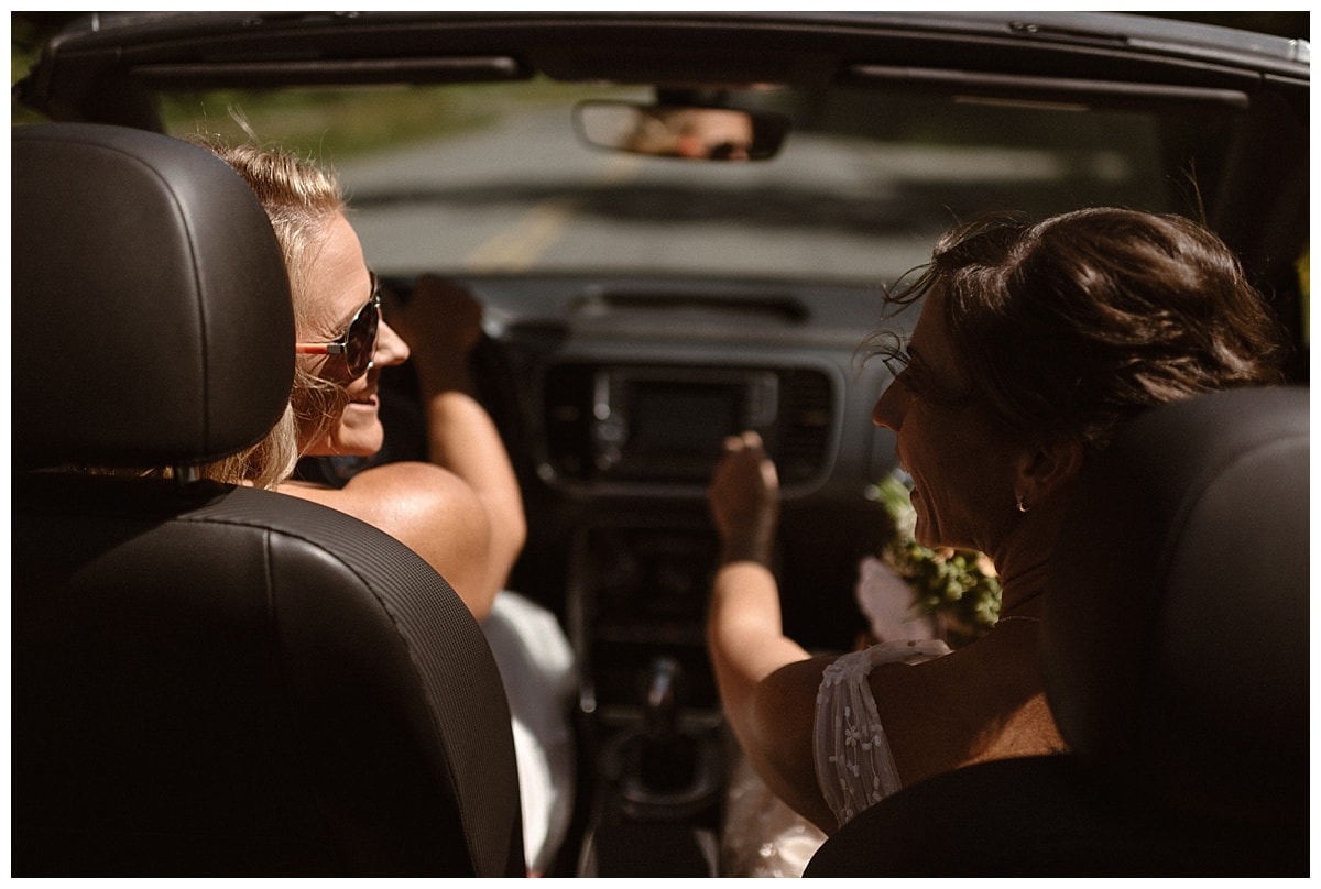 Two bride's driving in a car, smiling at each other, in Tofino, Canada. 