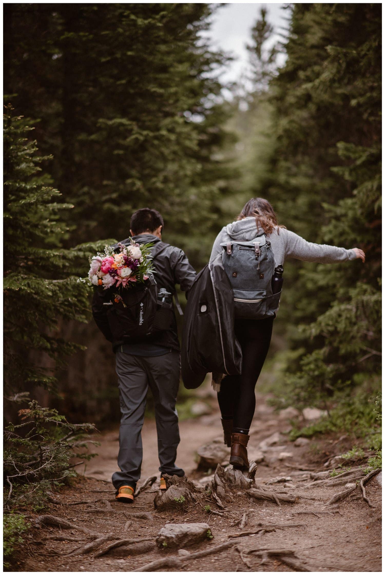Bride and groom hold hands while hiking on a trail near Boulder, Colorado on their elopement day. 