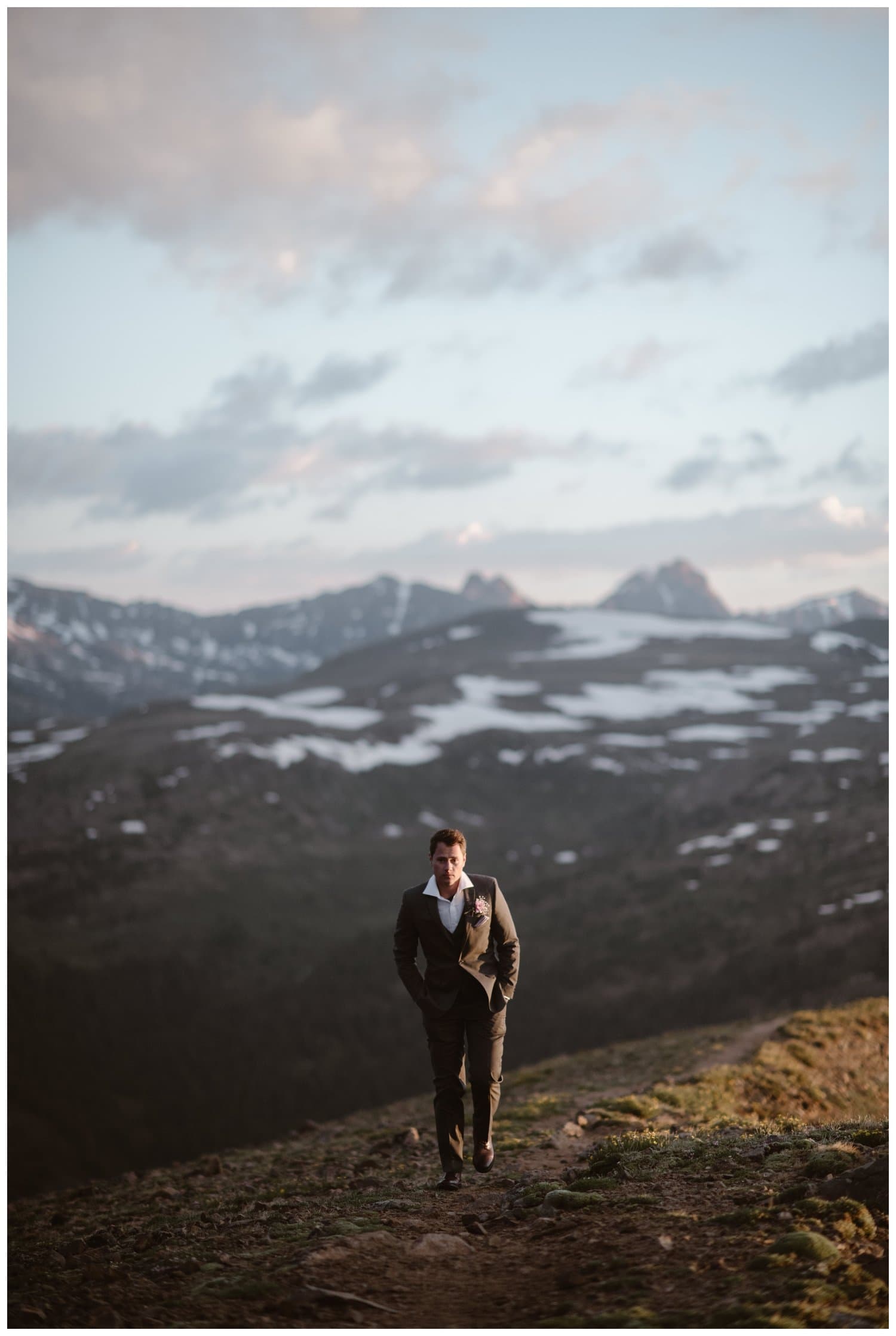 Groom standing on mountains and wearing a dark grey suit during a sunrise hiking elopement near Aspen, Colorado. 