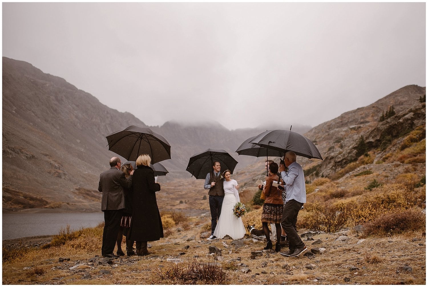 Family surrounds bride and groom during their ceremony with fog and mountains in the background. 