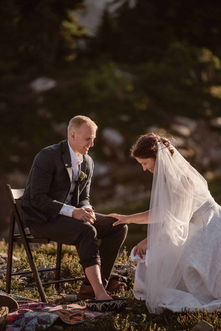 Bride washes the groom's feet on during their elopement ceremony at the base of Mount Shuksan in Washinton. 