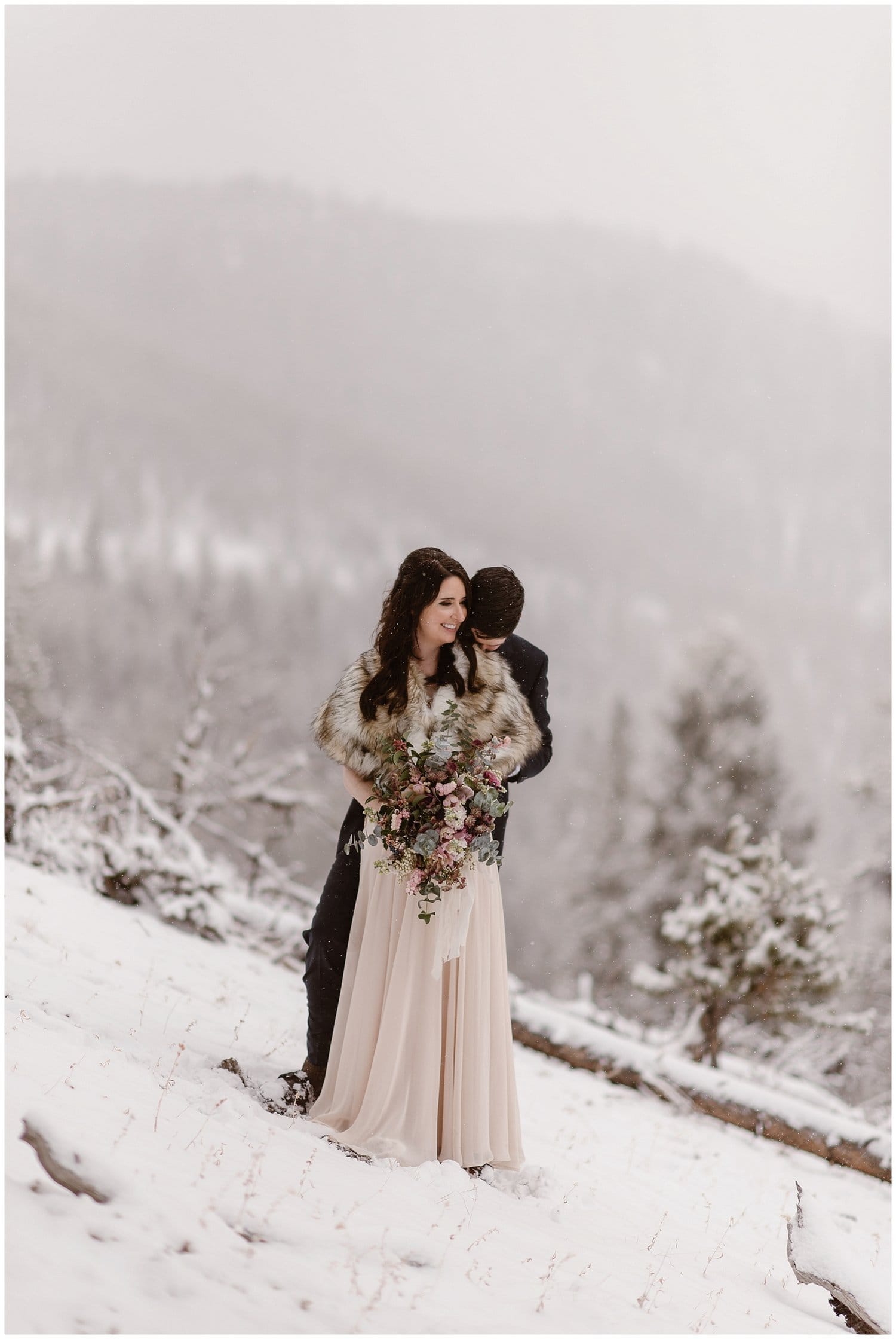 Bride and groom embrace during snow storm on their elopement day. 