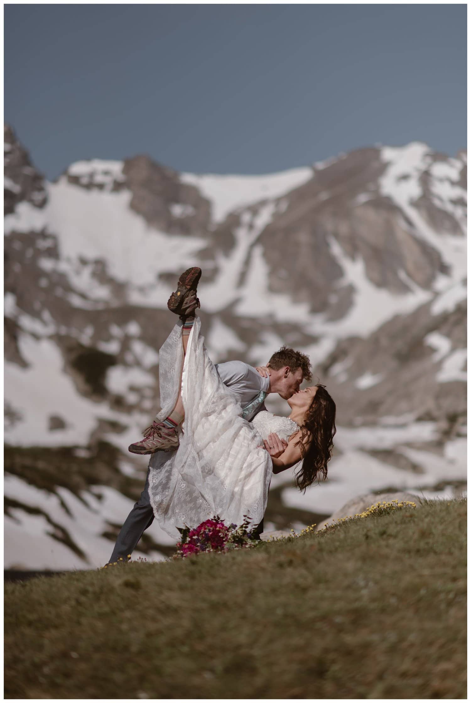 Groom holds bride and dips her down for a kiss at the Indian Peaks in Colorado. 