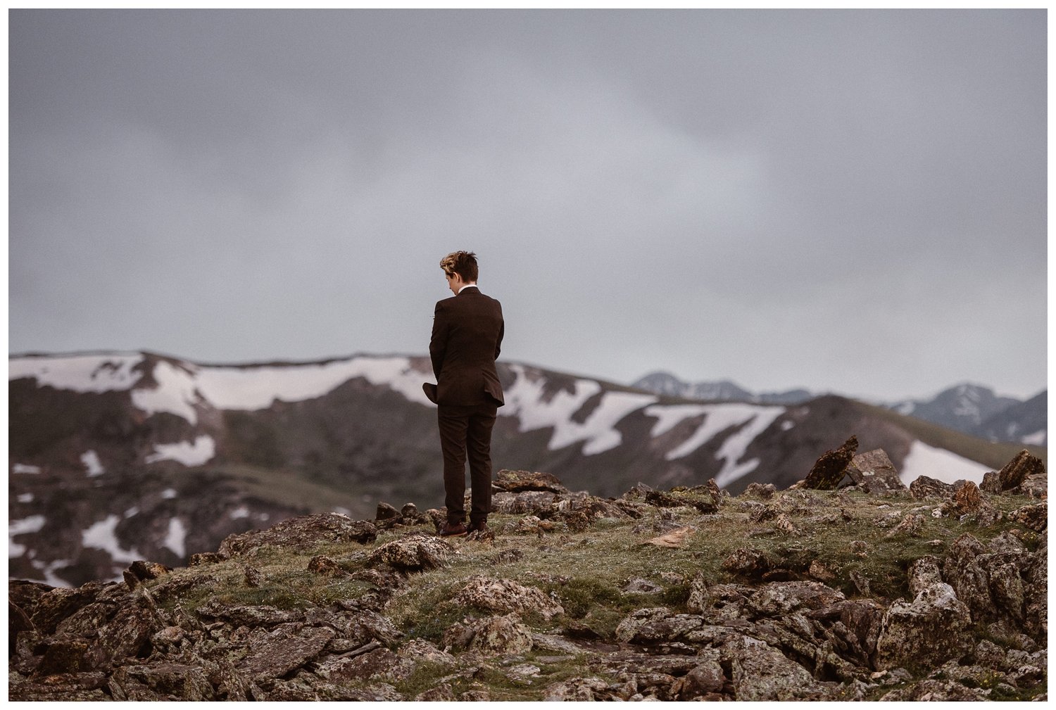 Bride wearing suit facing the mountains in the background at Trail Ridge Road. 