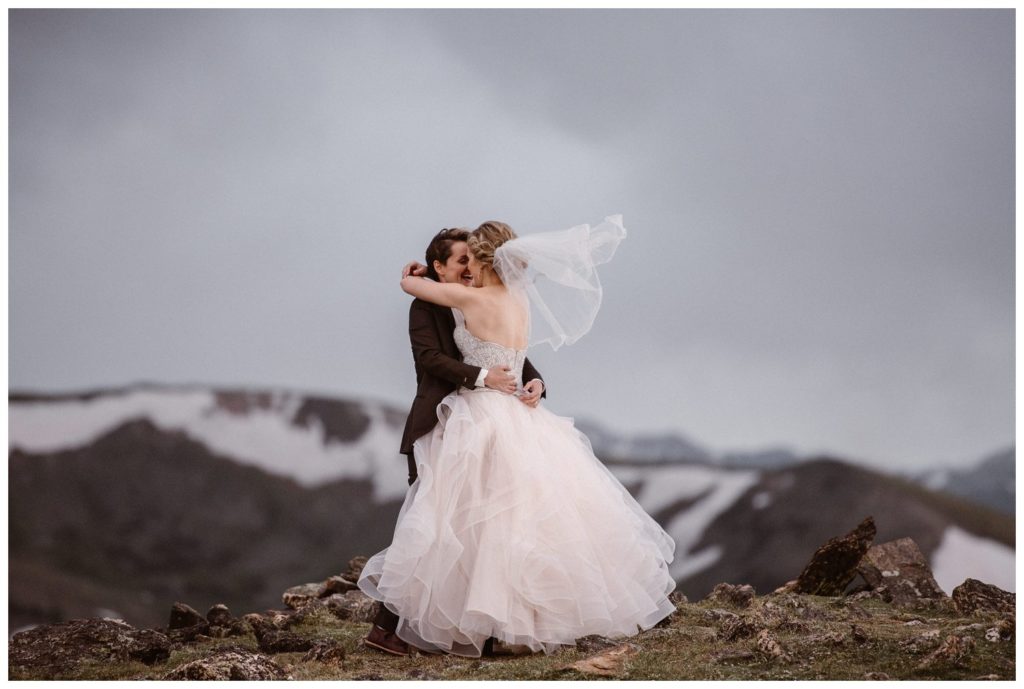 Two bride embrace as they have a first look on their elopement day at Trail Ridge Road, in Rocky Mountain National Park, Colorado. 