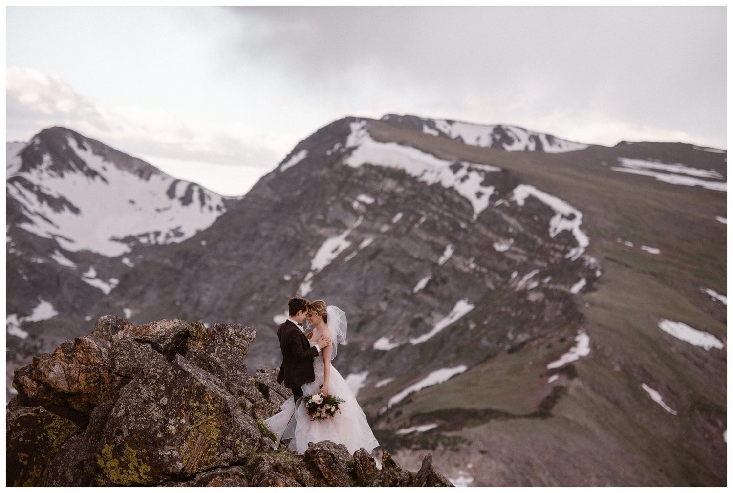 Two brides embrace on a cliff at Trail Ridge Road in Rocky Mountain National Park, Colorado.