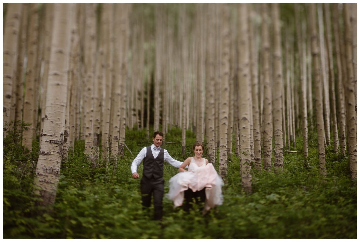 Bride and groom run through an aspen forest near the Maroon Bells, in Colorado. 