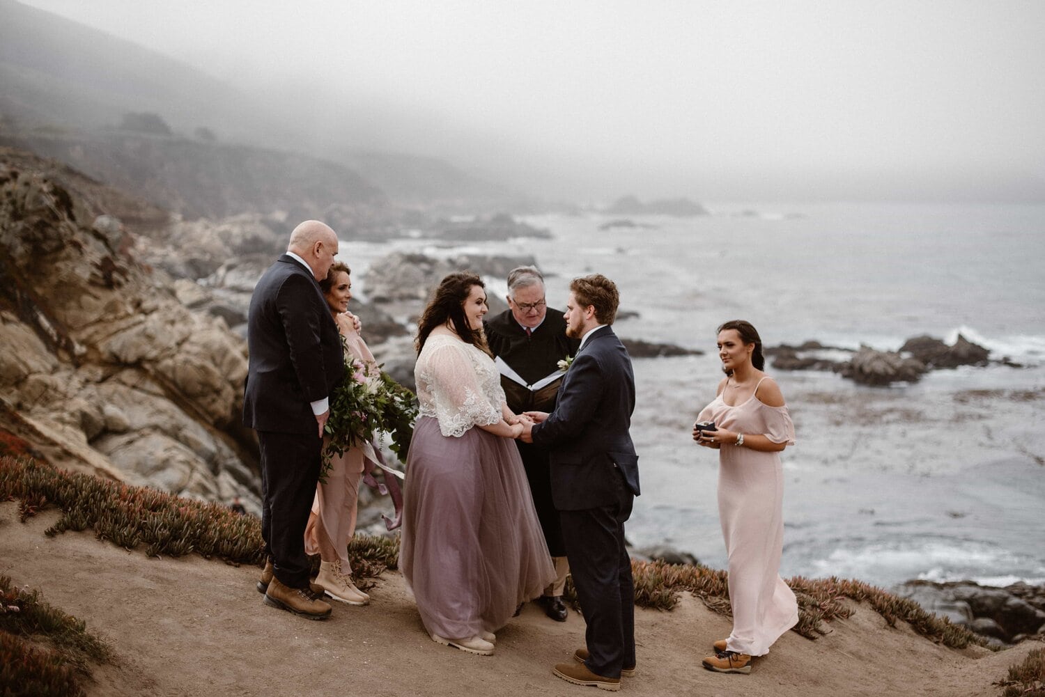 Bride and groom are surrounded by their friends and family during a private ceremony on the beach in Big Sur, California. 
