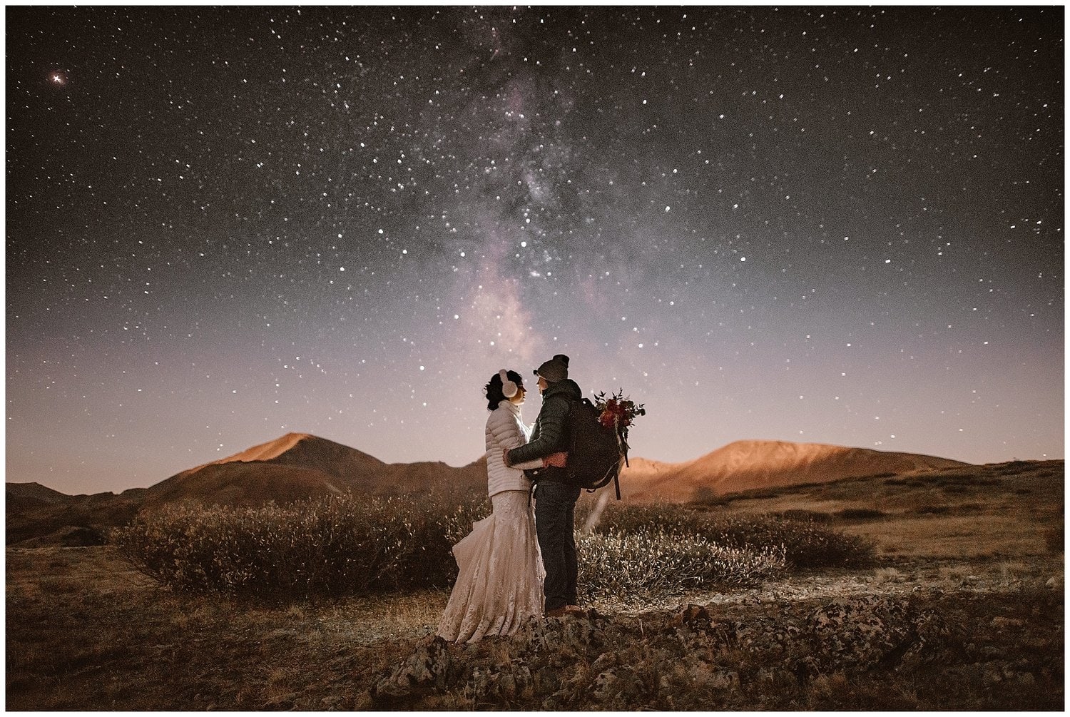 Bride and groom face each other  and embrace at night with stars in the sky. 