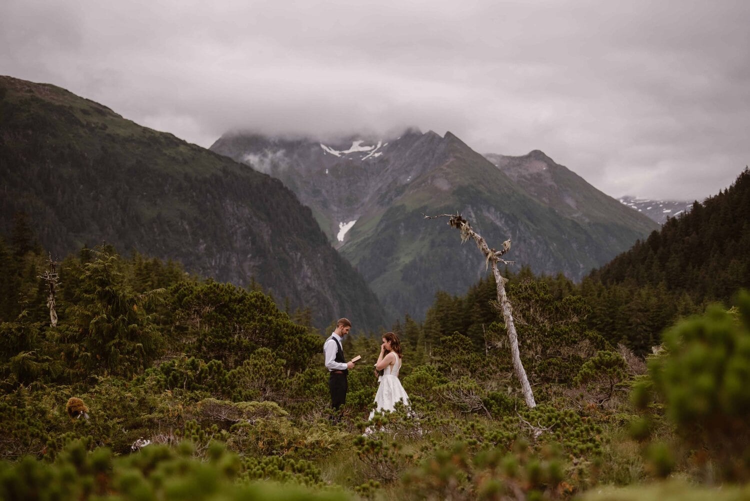 Groom reads vows to bride in the mountains.