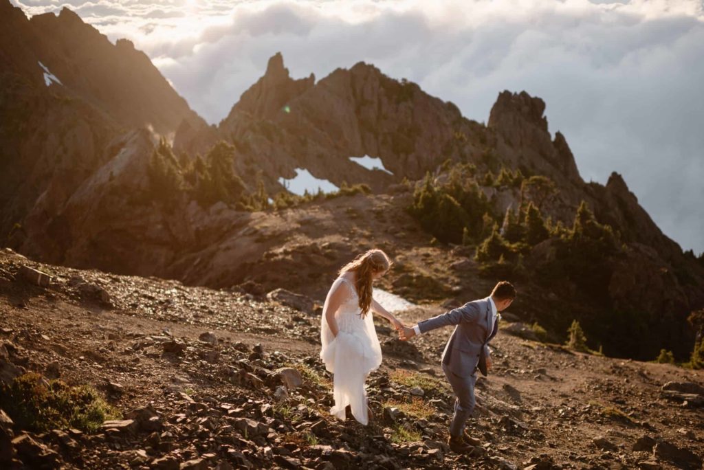Bride and groom hold hands and hike on trail at Mt. Ellinor at Olympic National Park. 