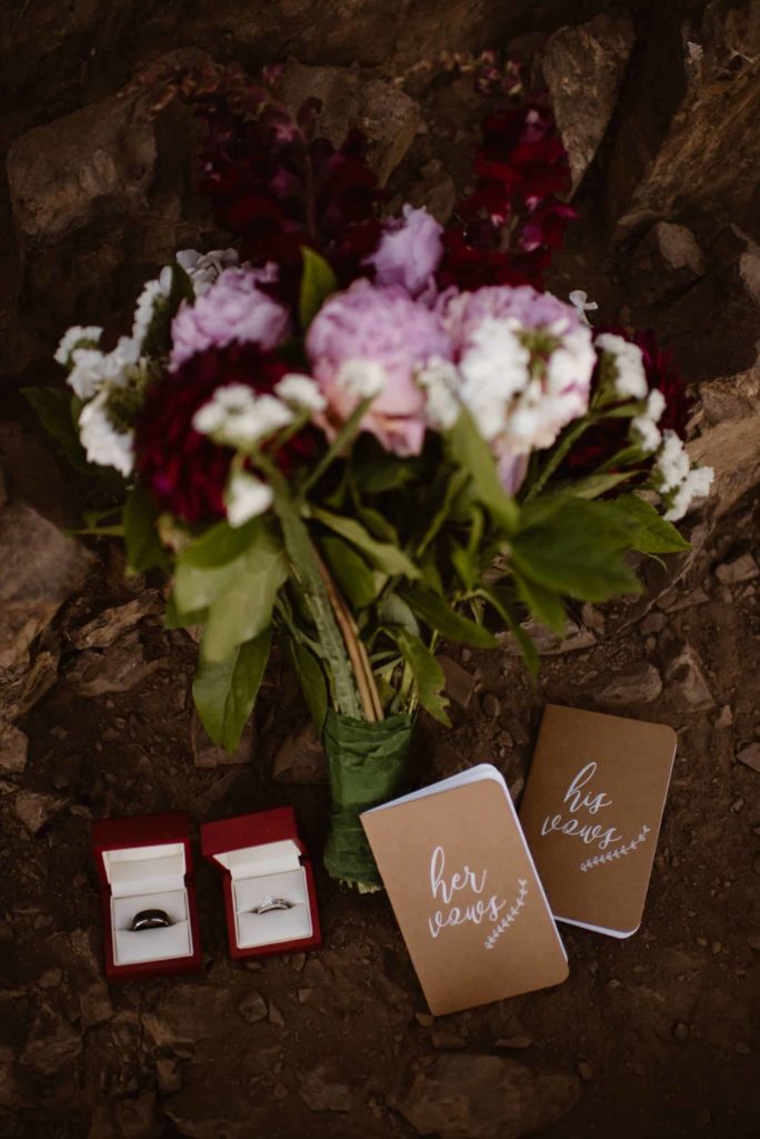 Flat lay of bride and groom's vow books, rings, and the bride's bouquet. 
