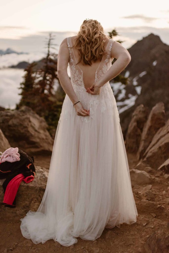Bride zips up her dress on Mt. Ellinor.