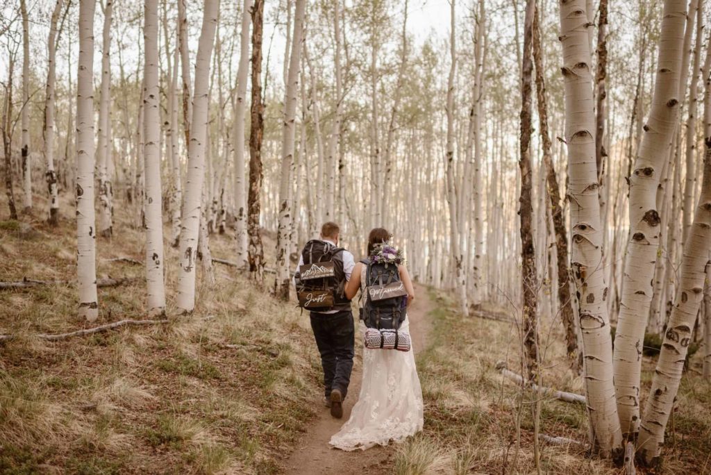 Bride and groom hiking through an aspen grove. 