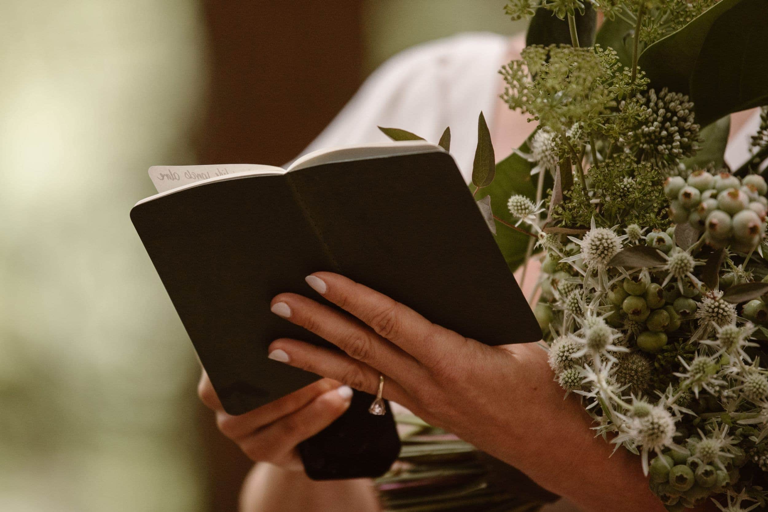 Close-up of bride holding her vow book and bouquet during elopement ceremony.