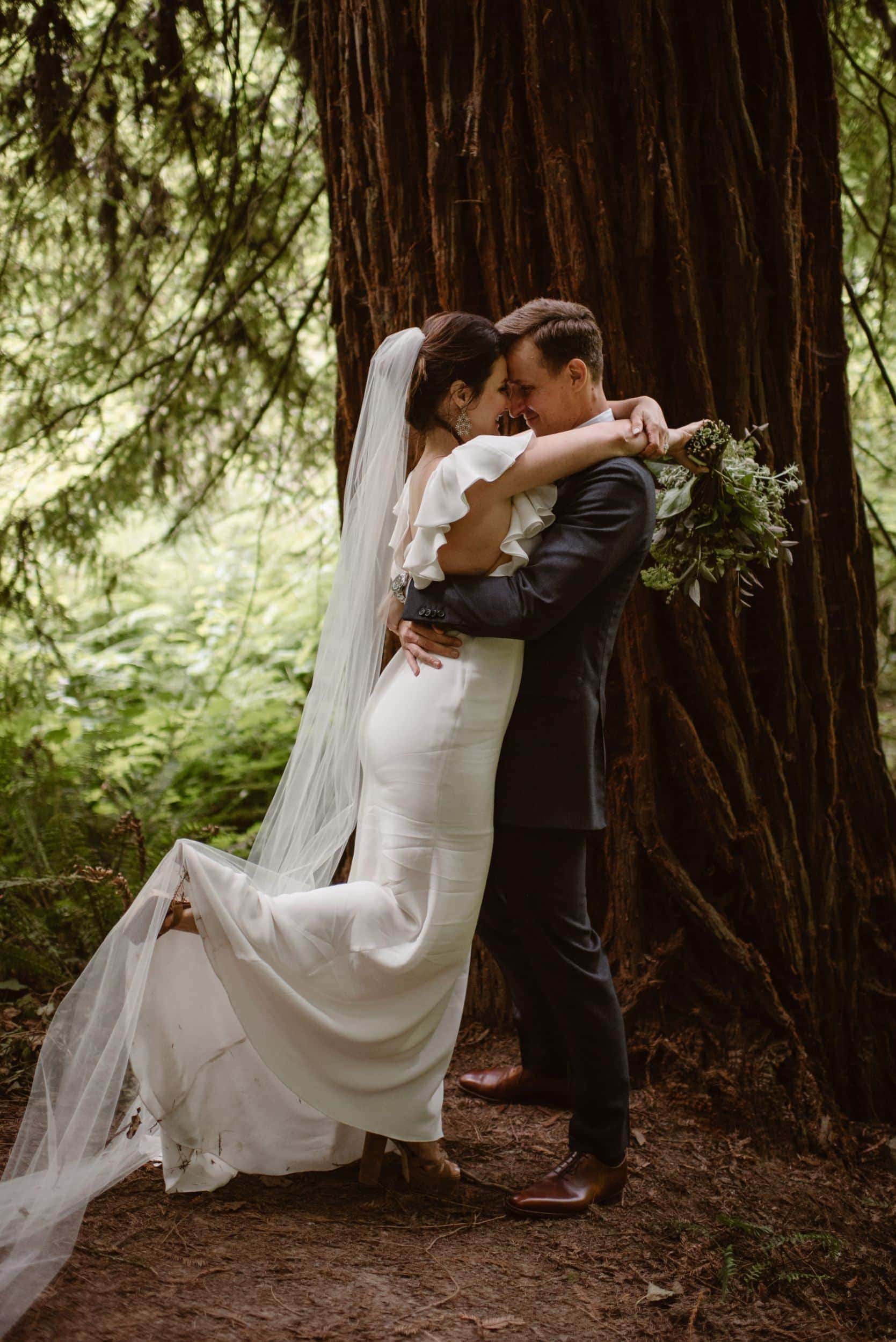 Bride and groom embrace in front of a redwood tree in Forest Park. 
