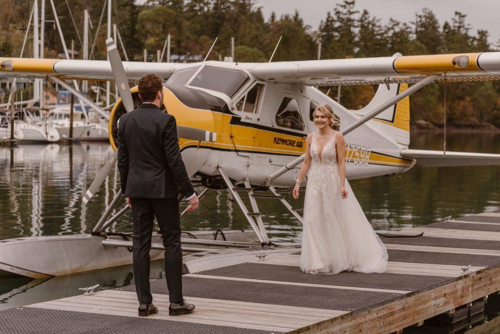 Bride and groom walk towards each other on dock next to floatplane on Ross Lake.
