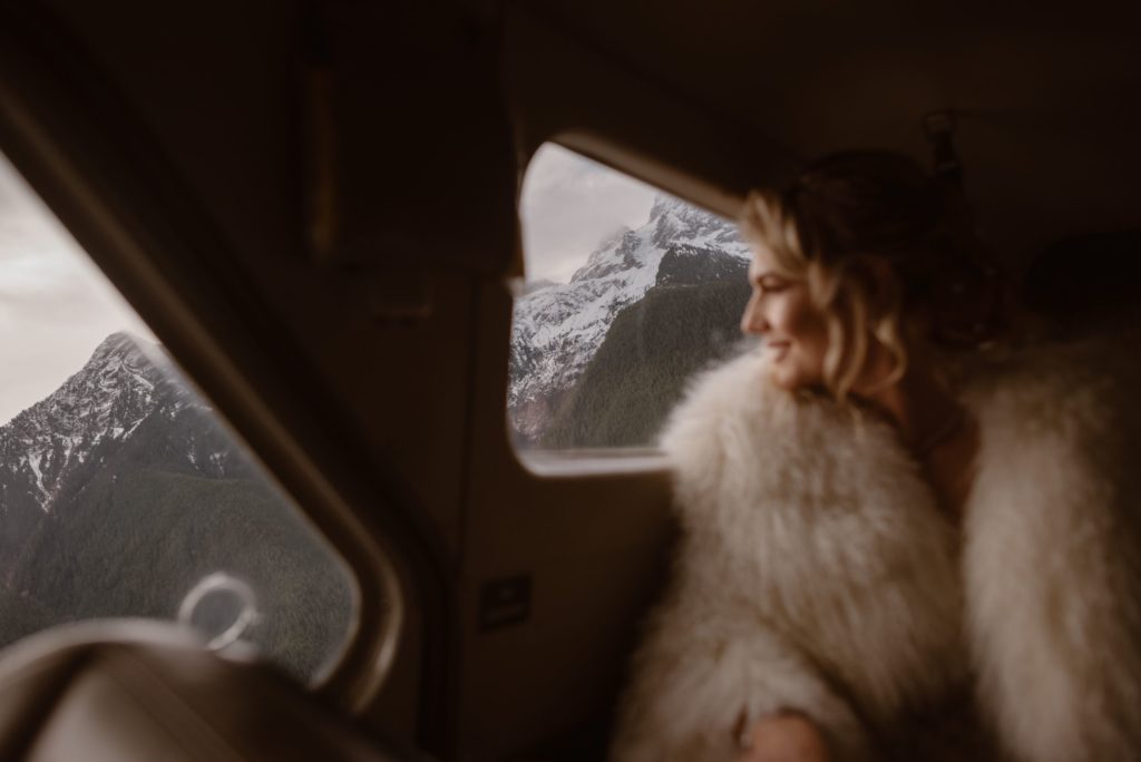 Bride looks out of floatplane window at mountains. 