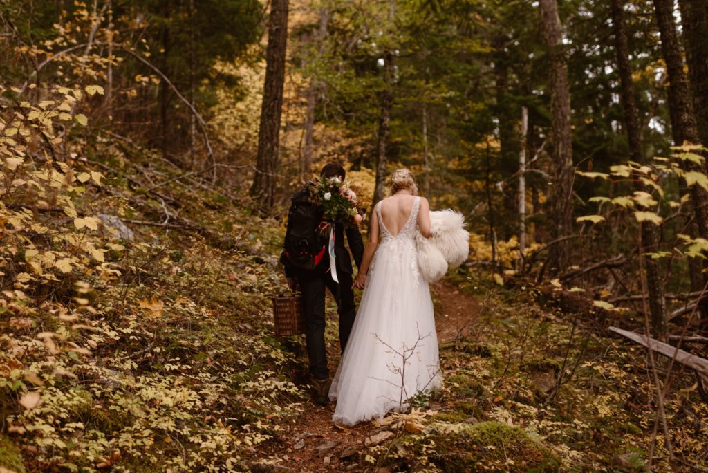 Bride and groom holding hands and walking on trail through forest on Orcas Island. 