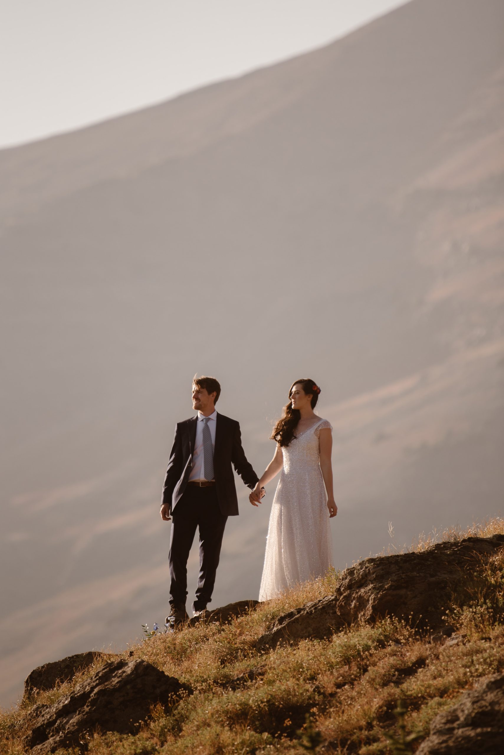 Bride and groom hold hands and look out at landscape in Crested Butte, Colorado. 