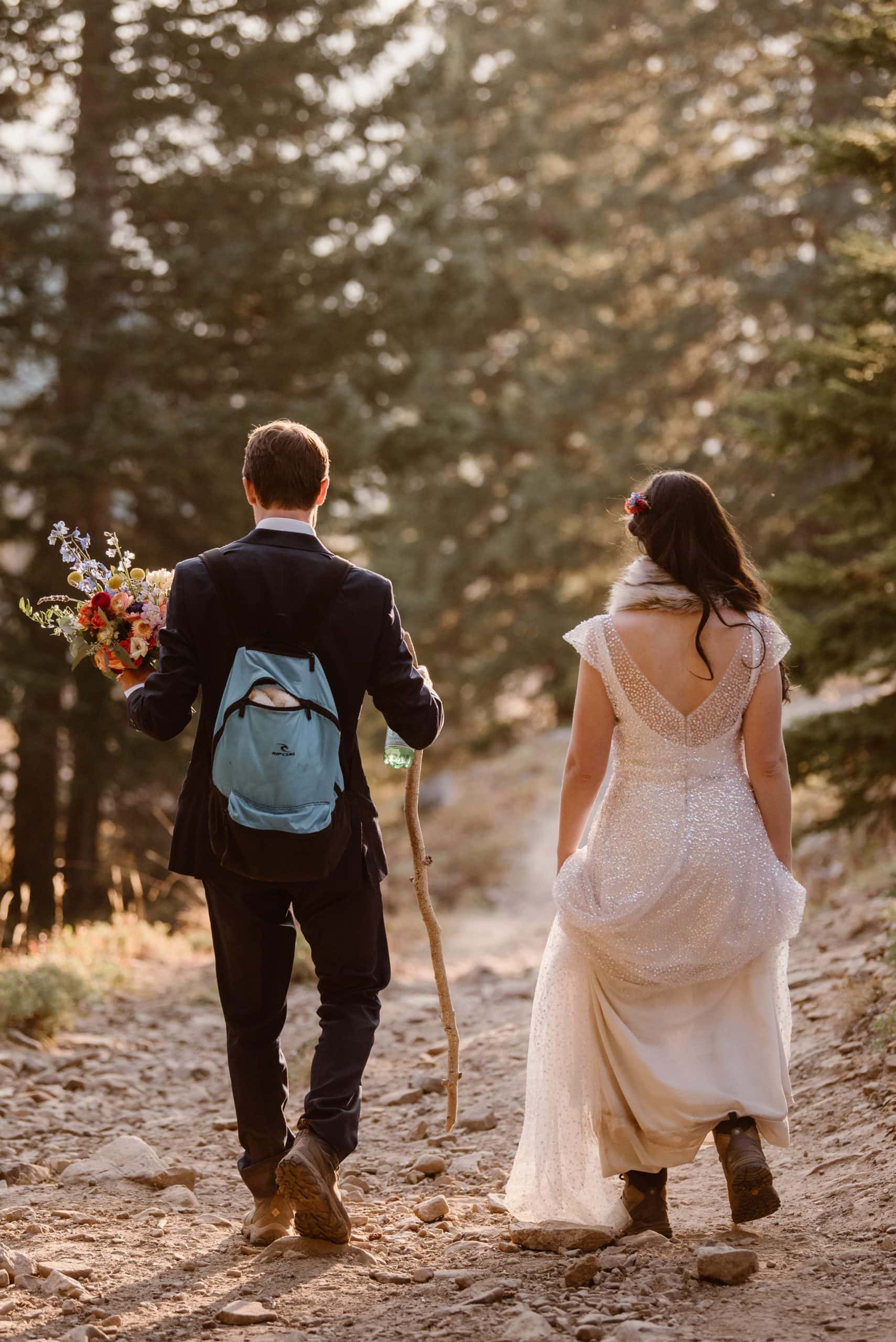 Bride and groom hike on trail through a forest in Crested Butte, Colorado. 